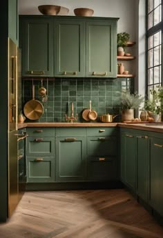 a kitchen with green cabinets and gold pots on the counter top, along with wooden flooring