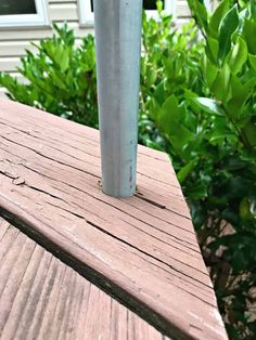 a metal pole sitting on top of a wooden deck next to shrubbery and a house