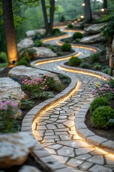 a stone path with lights in the middle and flowers on each side, surrounded by trees