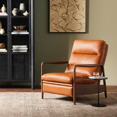 a brown leather chair sitting in front of a book shelf with vases on it