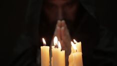 a person with their hands together in front of some lit candles that look like they are praying