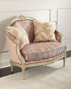 a chair with pillows on top of it in front of a white wall and rug