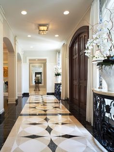 an elegant hallway with black and white tile flooring, chandelier and vases