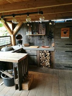 an old fashioned kitchen with wood stacked on the floor and lights hanging from the ceiling