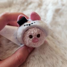 a hand holding a small stuffed animal in a white fur covered area with black writing on it