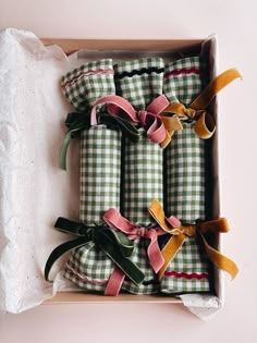 four wrapped presents in a box with ribbon tied around the edges and bows on them