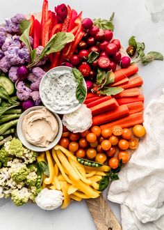 a platter with vegetables and dips on it