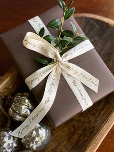 a present wrapped in brown paper and tied with a white ribbon sits on a wooden tray