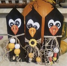 three black and white paper bags with faces on them sitting next to pumpkins in the background