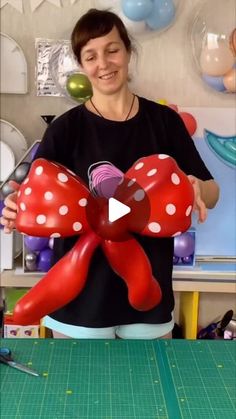 a woman holding a large red bow on top of a table