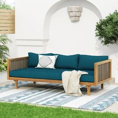 a blue couch sitting on top of a green rug next to a potted plant