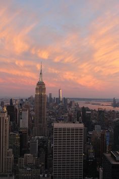 the city skyline is shown at sunset with pink clouds in the sky and skyscrapers