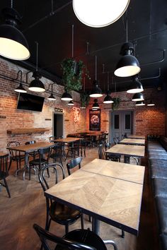 the interior of a restaurant with tables, chairs and televisions hanging from the ceiling