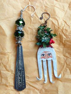 two christmas ornaments hanging from hooks on a piece of brown paper with some green and red decorations