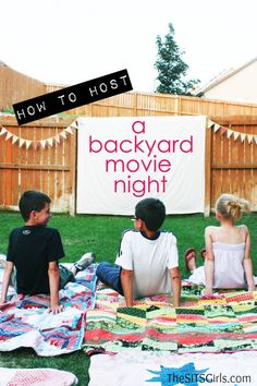 three children sitting on the grass in front of a backyard movie night sign