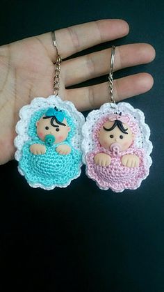 two crocheted keychains in the shape of babies are being held by someone's hand