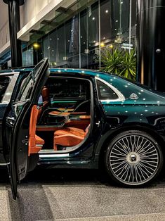 a black car with its door open on display at an auto show in the city