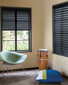 a room with two windows, a chair and a drum