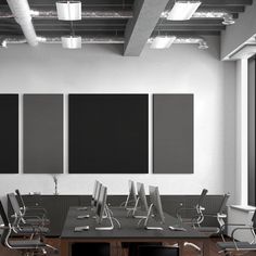 an empty conference room with chairs and desks in front of three blank canvases on the wall