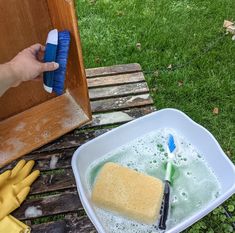 a person holding a blue and white toothbrush next to a tub of soap