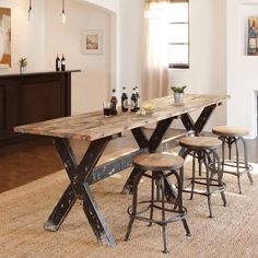 a dining table with four stools in front of it and bottles on the counter