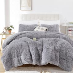 a bed with grey comforter and pillows in a room