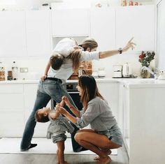 three people in a kitchen with one holding the other's hand and pointing at something