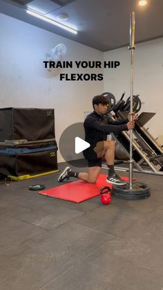 a man squats on the ground in front of an exercise machine and holds his leg up