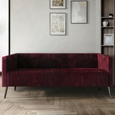 a red couch sitting in front of a book shelf on top of a hard wood floor