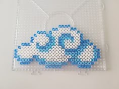 a piece of art made out of legos on a white surface with blue and white beads