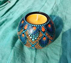 a candle sitting on top of a table next to a blue and orange vase with dots