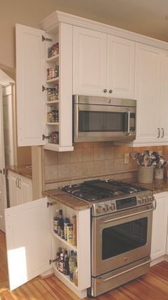 a kitchen with white cabinets and stainless steel stove top oven in the middle of it