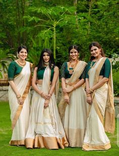 three women standing next to each other in white and green sari dresses with gold trims