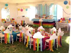 a party tent with tables and chairs decorated in rainbow colors