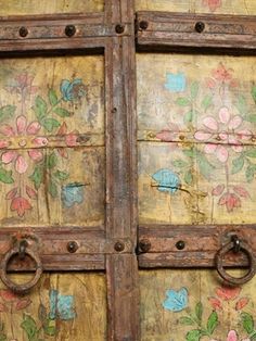 an old wooden door with flowers painted on it's side and two metal handles