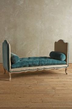 a blue couch sitting on top of a hard wood floor next to a white wall