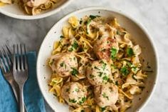 two bowls filled with pasta and meatballs on top of a white marble countertop