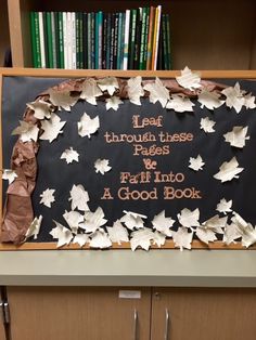 a blackboard with white leaves on it in front of a bookshelf filled with books