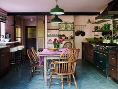 a dining room table and chairs in a kitchen next to an oven with pots on it