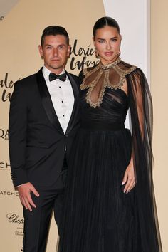 a man and woman standing next to each other on a red carpet wearing tuxedos