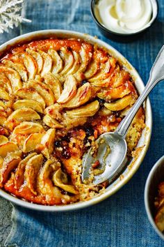 an apple cobbler in a white dish with two bowls of ice cream on the side