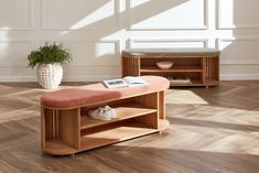 a wooden bench sitting on top of a hard wood floor next to a potted plant