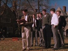 a group of young men standing next to each other in front of a large house