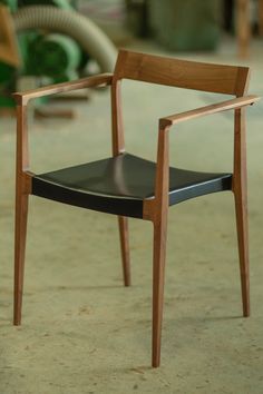 a wooden chair sitting on top of a cement floor next to a green object in the background