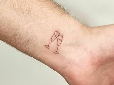 a small tattoo on the wrist of a man with two champagne glasses in each hand