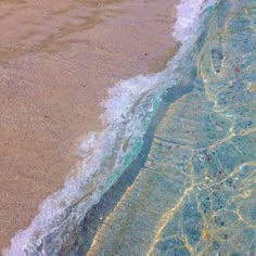 an aerial view of the water and sand on a beach with waves coming in to shore