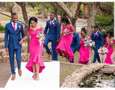 a man and woman in pink dresses are walking down the aisle with other people behind them