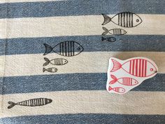 a red fish pin sitting on top of a blue and white striped blanket