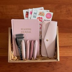 a pink box filled with lots of books and writing utensils on top of a wooden table