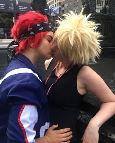 two people are kissing each other in front of a fountain with red hair and headbands